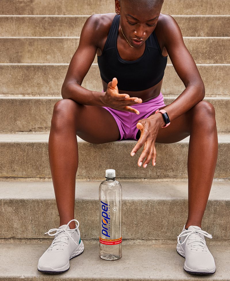An athlete recovering after a workout with a bottle of propel
